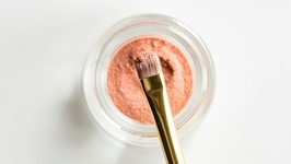 Tiegel mit Makeup-Puder und Pinsel