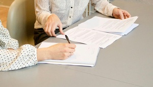 Personen sitzen mit Unterlagen bei Tisch