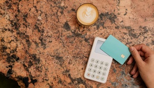 Hand hält Karte vor Bezahlgerät