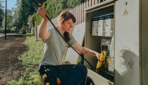 Elektrikerin, die an einem Stromkasten im Freien arbeitet