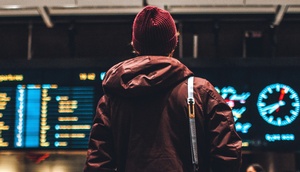 junge männliche Person blickt auf die Tabelle am Flughafen zu An- und Abflügen