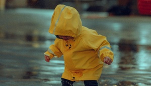 Kind in Regenjacke spielt im Regen