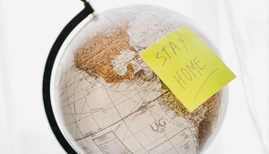 Globus mit Post-it mit der Aufschrift "Stay home"
