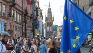 Menschen in einer Stadt, EU-Flagge rechts im Bild