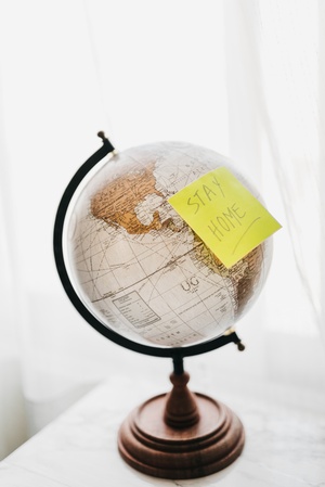 Globus mit Post-it mit der Aufschrift "Stay home", © Photo by BRUNO CERVERA on Unsplash