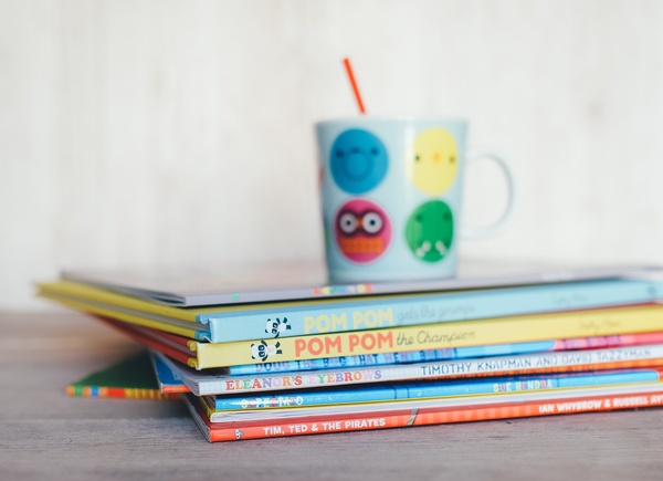 Kinderbuch mit einer Tasse oben auf dem Stapel, © Photo by Annie Spratt on Unsplash