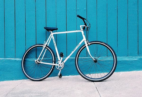 Weißes Fahrrad vor blauer Holzwand, © Carl Nenzen Loven auf Unsplash