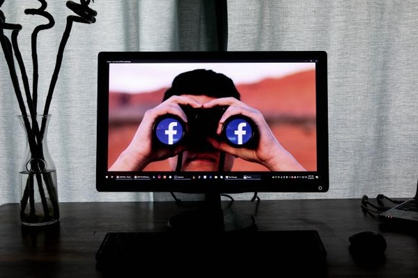 Computerbildschirm, Mann mit Fernglas, facebook Logo auf Linsen, © Glen Carrie