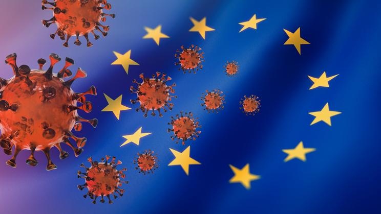 Abb.: Coronavirus, im Hintergrund die EU Flagge, © https://socialistvoice.ie/2020/07/the-eu-and-covid-19/