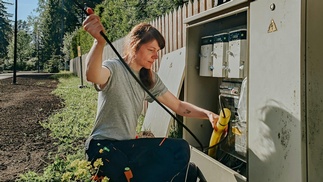 Elektrikerin, die an einem Stromkasten im Freien arbeitet