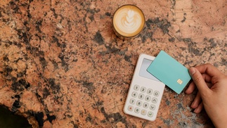 Hand hält Karte vor Bezahlgerät