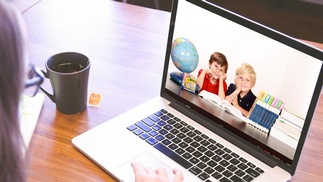 Laptop zeigt 2 Kinder beim Lernen
