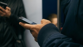 Mann hält Smartphone in U-Bahn