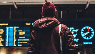 junge männliche Person blickt auf die Tabelle am Flughafen zu An- und Abflügen