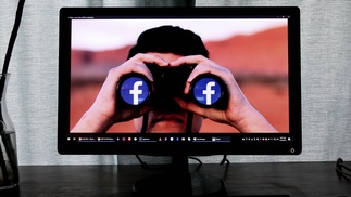 Person schaut durch Fernglas mit Facebook-Logo